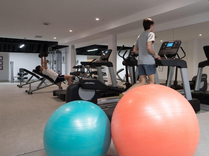 Siłownia z różnym sprzętem do ćwiczeń i kolorowymi piłkami fitness na pierwszym planie.