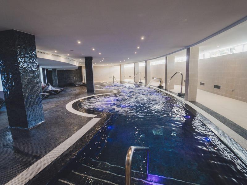 Nowoczesny kryty basen z nastrojowym oświetleniem i dużymi oknami w hotelu