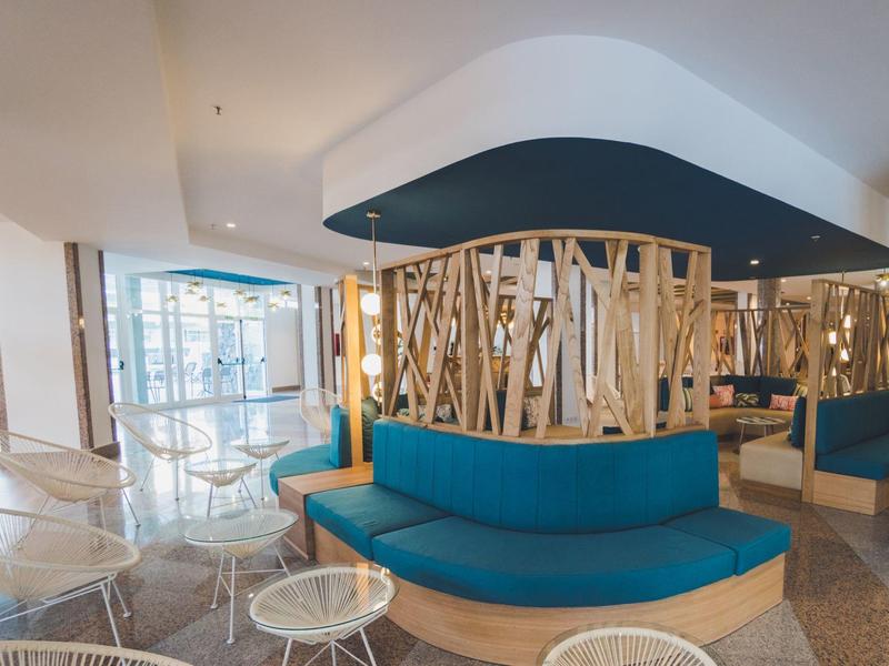 Nowoczesna przestrzeń lounge z niebieskimi ławkami i drewnianymi akcentami w hotelu.