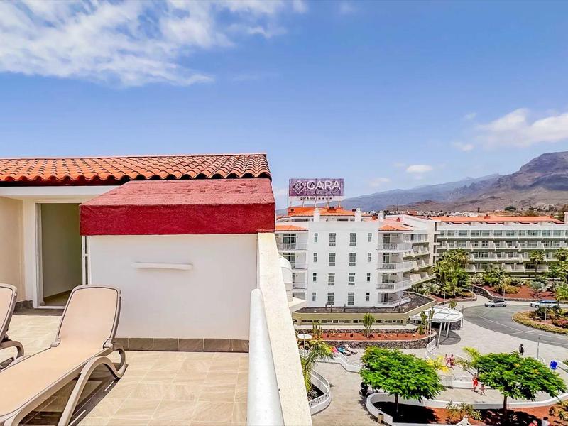 Balkon z leżakami, widok na hotele i góry pod błękitnym niebem