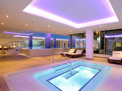 Modern spa area with illuminated jacuzzi and swimming pool in luxury hotel.