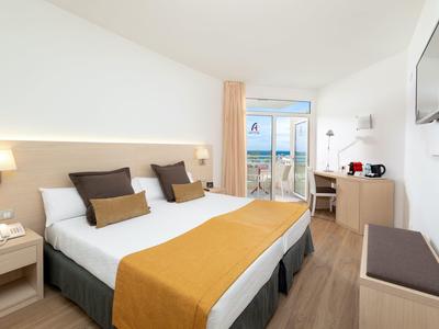 Modern hotel room with large double bed, desk, balcony, and TV.