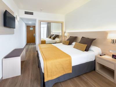 Modern hotel room with double bed, wood flooring, and flat-screen TV.