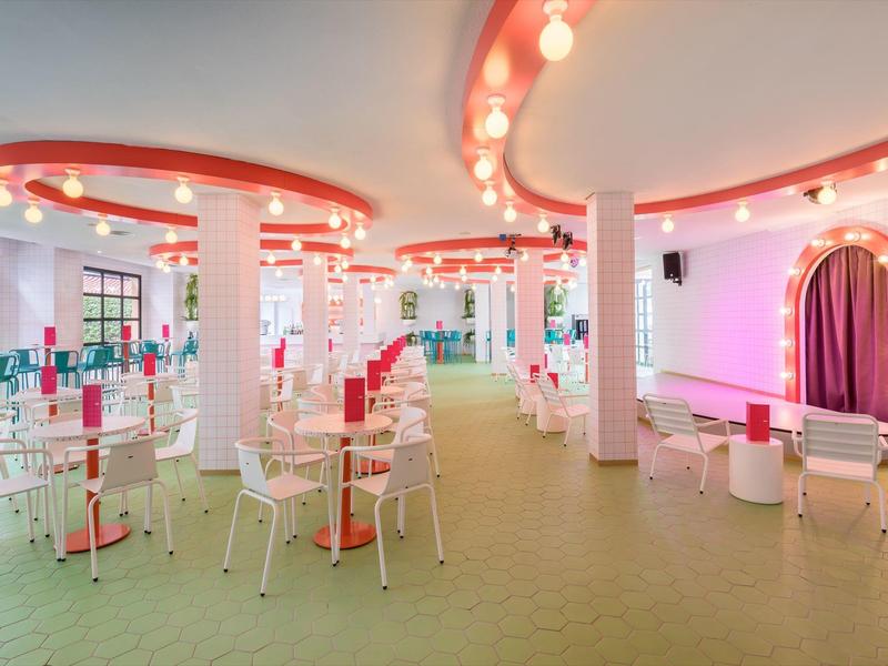 Jasne, nowoczesne wnętrze restauracji z różowym oświetleniem i białymi meblami.