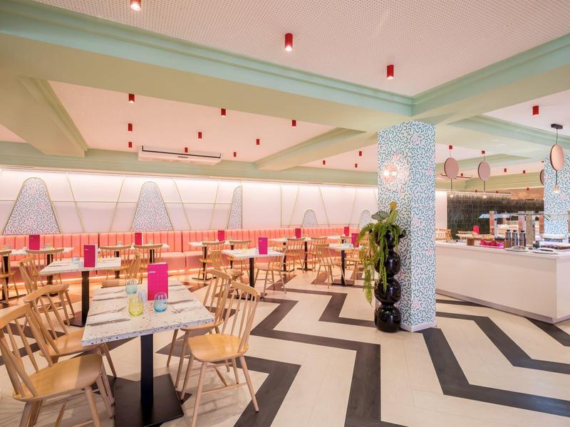 Jasne wnętrze restauracji z podłogą w jodełkę i drewnianymi stołami.