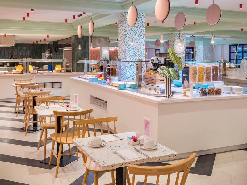 Nowoczesne wnętrze bufetu hotelowego z drewnianymi stołami i elegancką dekoracją.