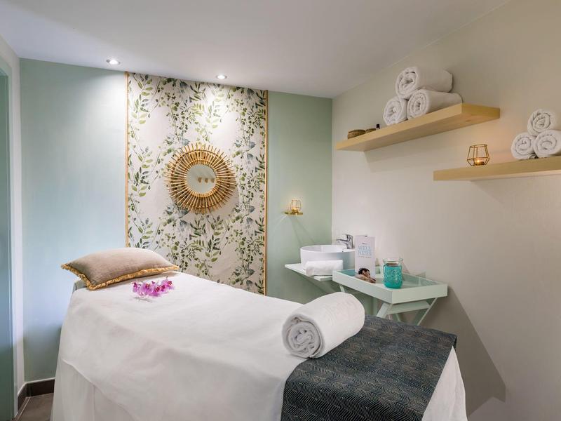 Pokój spa z łóżkiem do masażu, ręcznikami i zen dekoracją.