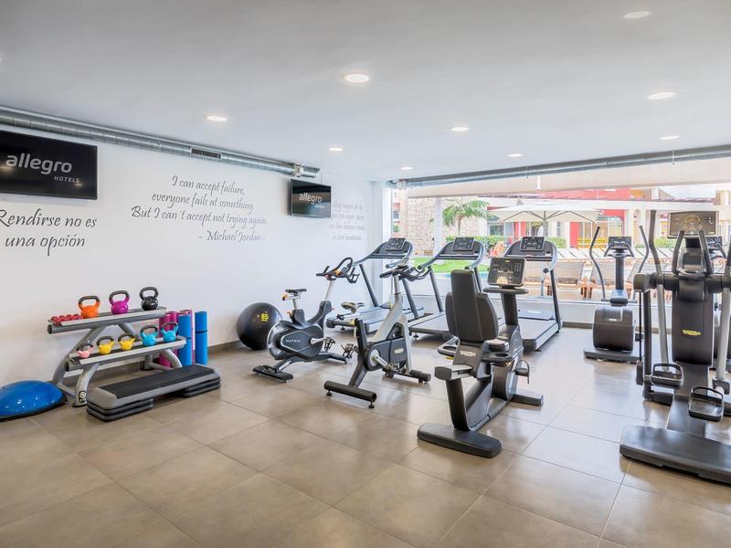 Jasna siłownia z nowoczesnym sprzętem i dużym oknem z widokiem na zewnątrz.