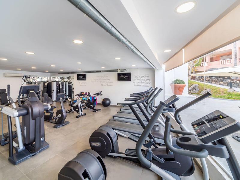 Nowoczesna siłownia z maszynami i widokiem na zewnętrzny taras.