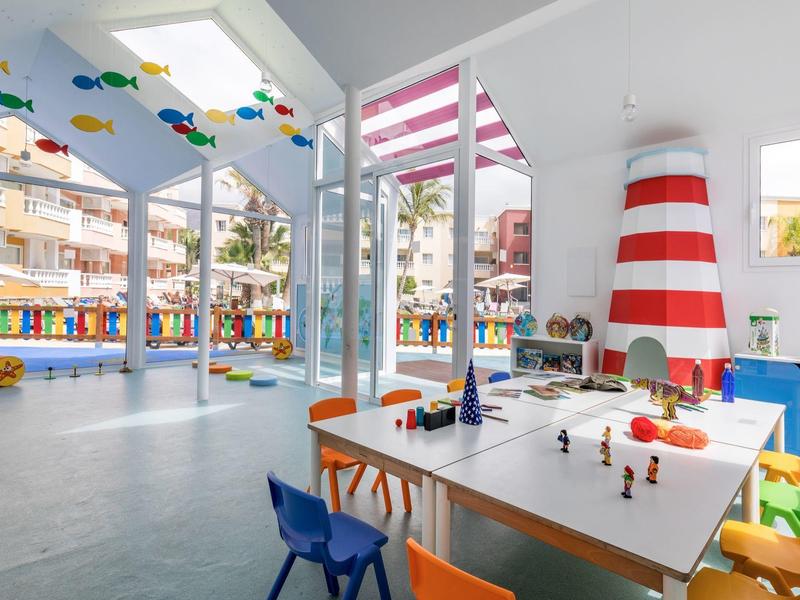 Kolorowa sala zabaw obok czerwono-białej latarni morskiej z widokiem na budynki na zewnątrz.