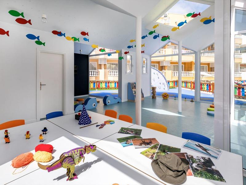 Kolorowa sala rekreacyjna z stołami, krzesłami i zawieszonymi dekoracjami ryb.