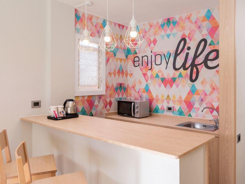 Nowoczesny kącik kuchenny z drewnianym blatem i kolorową ścianą "enjoy life".