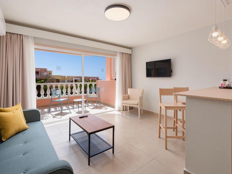 Jasny salon z kanapą, stolikiem kawowym, barkiem i słonecznym balkonem.