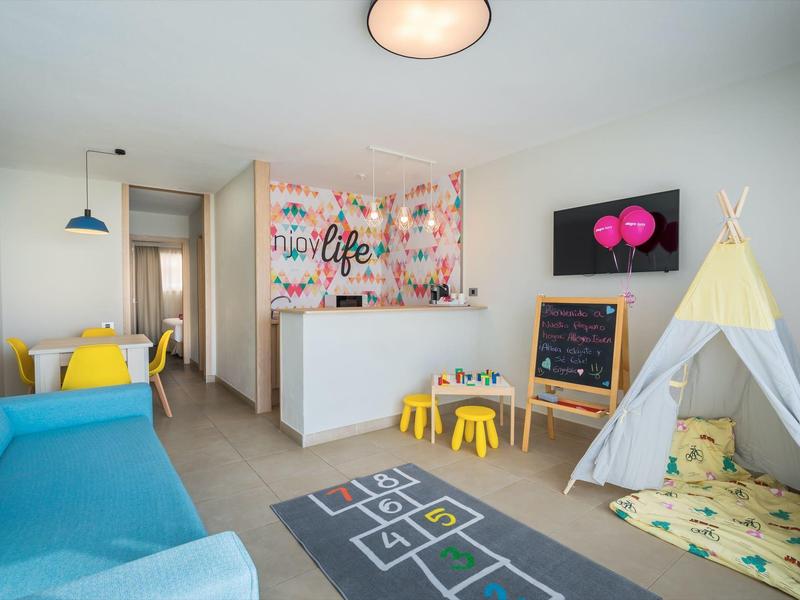 Jasny pokój zabaw z niebieską sofą, dywanem z grą w klasy i namiotem dla dzieci.