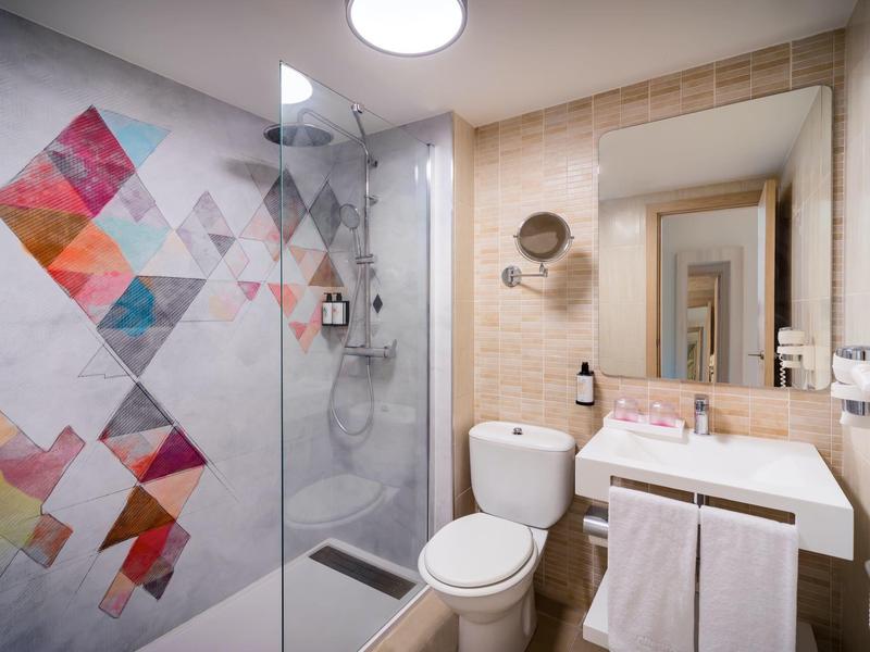 Nowoczesna łazienka hotelowa z prysznicem, toaletą, umywalką i ozdobnymi ścianami.