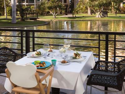 Terrasse mit eingedecktem Tisch und Stühlen neben einem Teich in einem Hotelgarten.