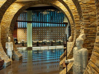 Hotel lobby met bakstenen bogen en decoratieve beelden bij de ingang.