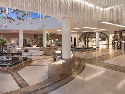 Ruime hotel lobby met moderne zitplekken, waterpartijen en elegante verlichting.