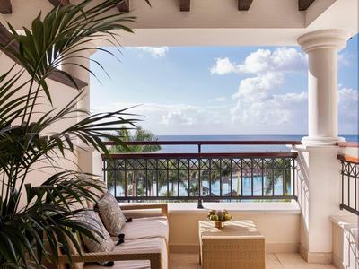 Gezellig balkon met zitplaatsen uitkijkend op palmbomen en helder uitzicht op de oceaan.