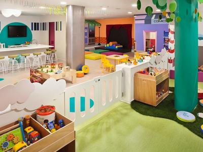 Kleurrijke speelkamer voor kinderen met speelgoed, kleine hekken en zithoeken in een hotel of resort.