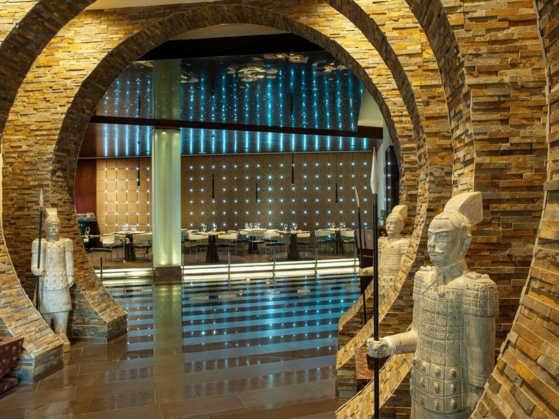 Hotel lobby met bakstenen bogen en decoratieve beelden bij de ingang.