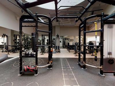 Large gym with various workout machines and mirrors on the walls.
