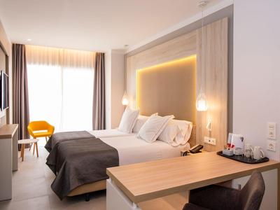Modern hotel room with double bed, wooden furniture, and yellow chair by window with curtains.