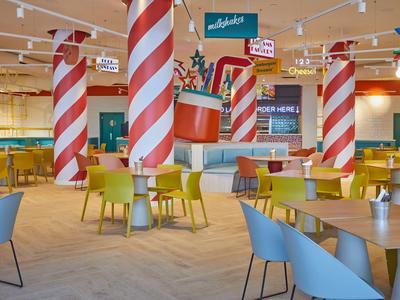 Bright restaurant with colorful chairs and red-and-white striped columns.