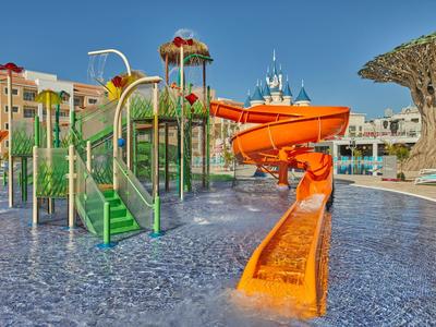 Colorful water playground with slides and play structures in hotel pool under clear sky.