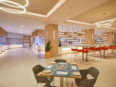 Modern breakfast area with tables and chairs in bright tones.