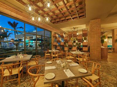 Cozy hotel restaurant with wooden tables and a view of the illuminated outdoor area at dusk.