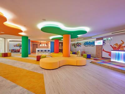 Světlá hotelová lobby s barevným sezením a sloupy, moderní a příjemný design.