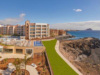 Luxusní pobřežní hotel s bazénem, zahradou a výhledem na moře a skalnaté pobřeží