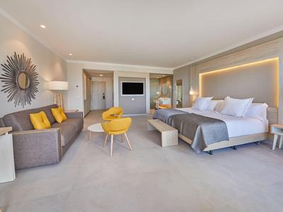 Světý hotelový pokoj s velkou postelí, posezením a moderním, minimalistickým designem.