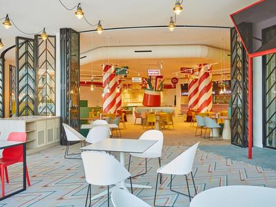 Moderní hotelová lounge s barevnými židlemi a elegantním osvětlením.