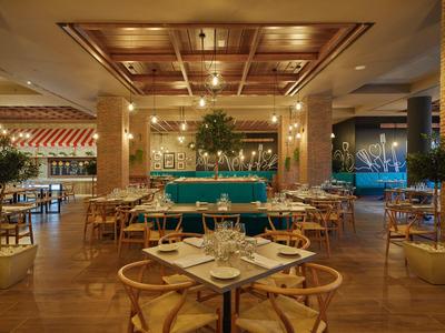 Elegantní hotelová restaurace s dřevěnými stoly, židlemi a stylovým osvětlením.