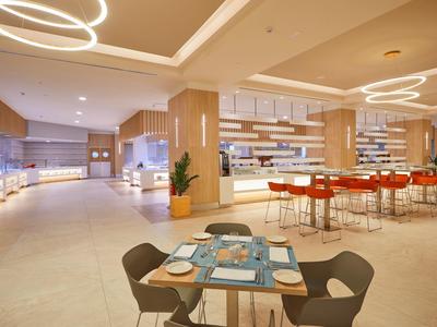 Moderní hotelová restaurace se stylovým osvětlením a stoly s modrými prostíráními.