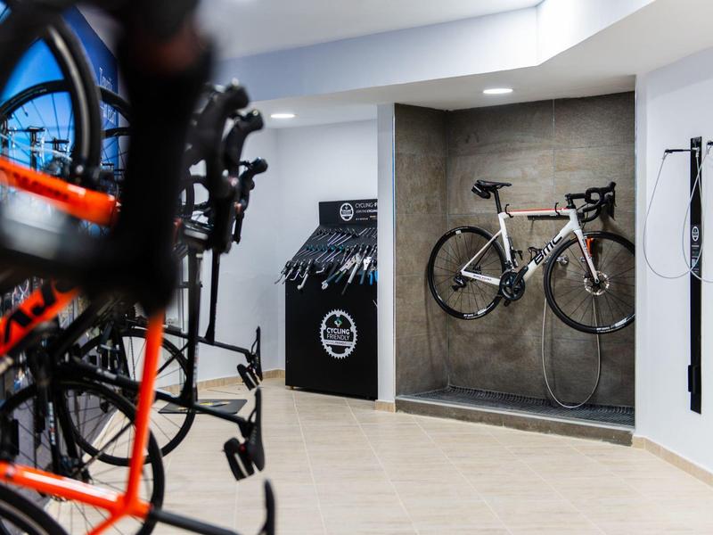 Moderner Fahrradraum mit mehreren Rennrädern an Wandhalterungen und hellem Bodenbelag.