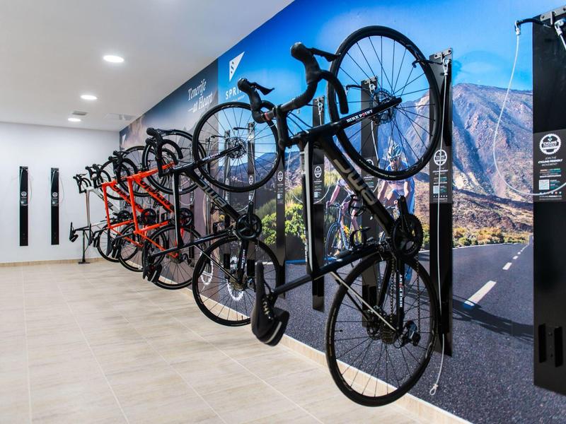 Mehrere Fahrräder hängen an einer modernen Wandhalterung vor einer Berglandschaft.
