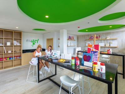 Modern bright art room with green ceiling accents and various art supplies.