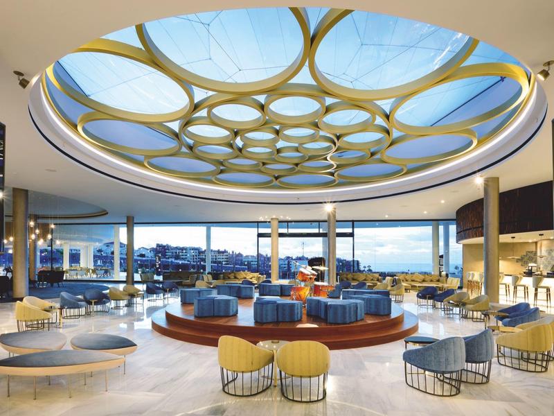 Moderne hotel lobby met ronde plafondlampen, stijlvolle zitplaatsen en grote ramen met uitzicht op buiten.