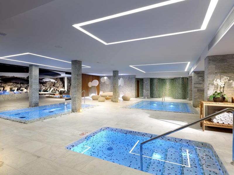 Moderne overdekte spa met zwembaden, jacuzzi's, relaxstoelen en sfeerverlichting.