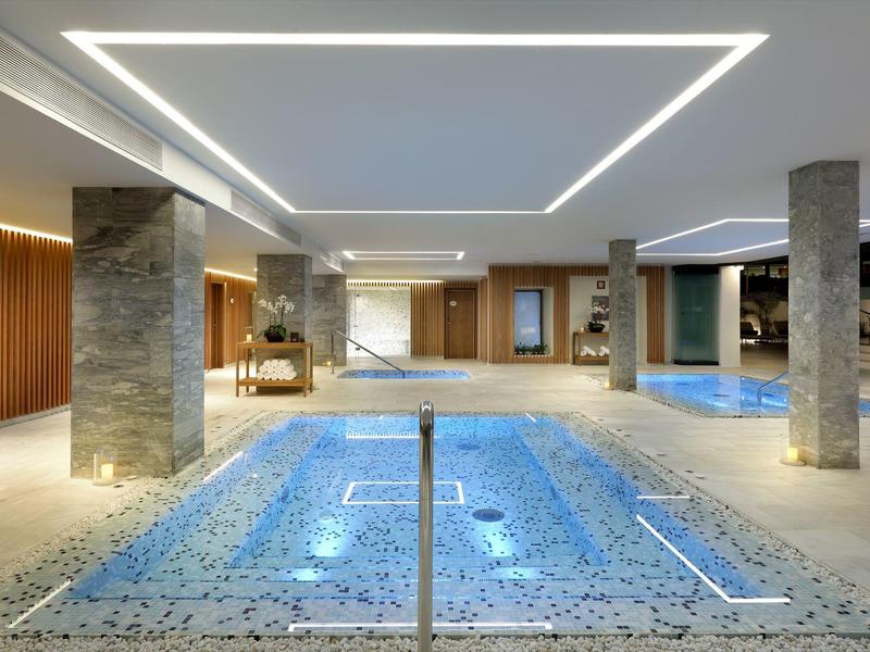 Overdekt spa zwembad met moderne verlichting en stenen pilaren in een luxe hotel.