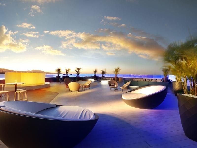 Moderne dakterras met ronde loungestoelen, planten en uitzicht op de oceaan bij zonsondergang.