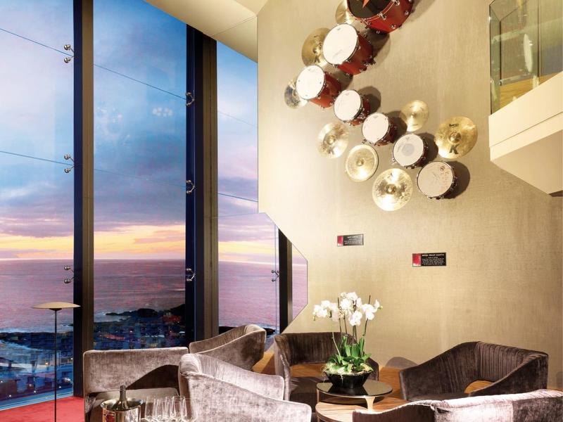 Moderne hotel lounge met grote ramen, comfortabele zitplaatsen en sfeervolle inrichting bij zonsondergang.