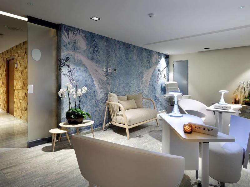 Moderne hotel lounge met witte fauteuils, een kleine tafel, orchideeën en een grote blauwe decoratieve muur.