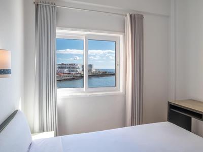 Camera d'hotel luminosa con vista sul porto e sull'acqua attraverso la finestra.