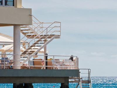 Balkon s schody nad mořem, část moderní budovy s čistými liniemi.