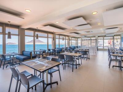 Ristorante luminoso con vista mare, arredamento moderno e grandi finestre.
