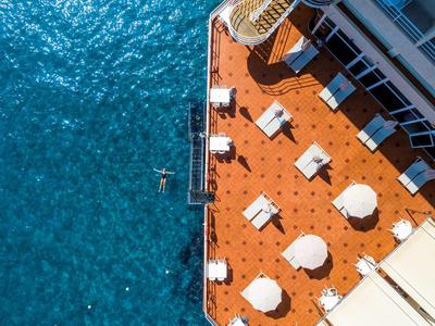 Pohled z ptačí perspektivy na hotelovou terasu s lehátky u vody